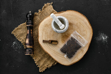 Wooden cross section with peppercorn in plastic package and mortar and mill
