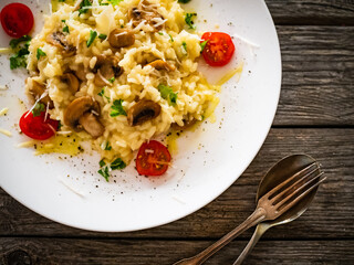 Risotto with white mushrooms, roast tomatoes and parmesan on wooden table
