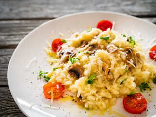 Risotto with white mushrooms, roast tomatoes and parmesan on wooden table
