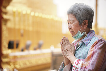 old asian senior woman traveler tourist praying at buddhist temple.