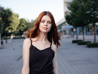 Fashionable Woman in a black dress walks down the street in the park in nature