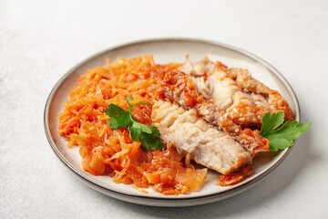 Fish pollock fillet with garnish stewed cabbage in a plate on the table. Healthy diet
