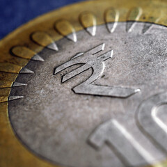 Translation of the inscription: rupee. Fragment of Indian 10 rupee coin with the sign of the national currency close up. Square illustration on the theme of money and economy in India. Macro