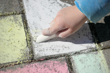 Kind malt mit Malkreide auf Pflastersteinen