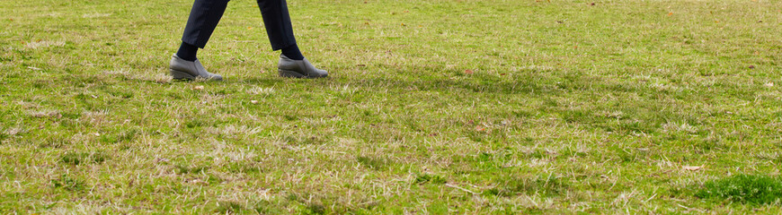 春の公園の芝生に歩いている女性の姿