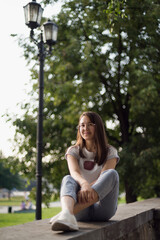 a beautiful Asian girl sits on the parapet against a background of green foliage