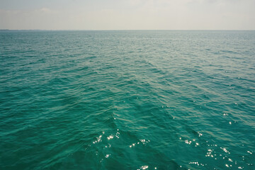 The surface of the water is calm in the middle of the sea. The sea is wide open, the horizon and the blue green turquoise water surface. Photos from a boat in the middle of the ocean. 