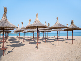 Summer landscape with straw umbrellas on the beach in Mangalia or Mamaia. Beach at the Black Sea in Romania.