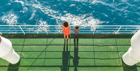 A boy and his mother stand on the deck of the ship and look at the sea.