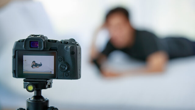 Asian blogger with smartphone recording video on bed