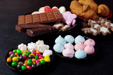 Harmful food. Sweets, chocolate bars, cookies and sweets.Dark background.