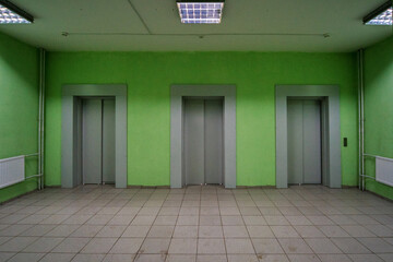 Three elevator doors in a residential building. Wide-angle view of modern elevators with doors, green walls. Elevators in the modern lobby of the house.