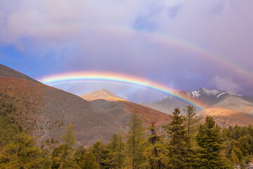 Beautiful rainbow in the mountains. Rain clouds.