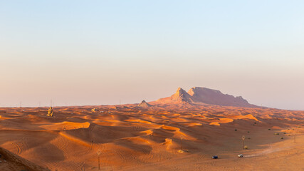 Fototapeta na wymiar Panorama of sunset over Fossil Rock mountain ridge and golden desert dunes, Sharjah, United Arab Emirates.