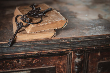 old vintage keys on an old battered book, antique wooden background. The concept of mystery and...