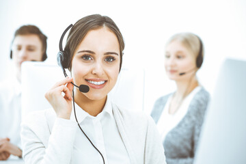 Call center. Group of diverse operators at work. Beautiful woman in headset communicating with...