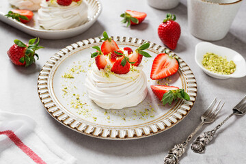 Perfect mini Pavlova cake with whipped mascarpone cream and fresh strawberry slices, sprinkled with crushed pistachios.