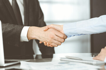 Unknown business man and woman are shaking hands finishing contract signing, close-up. Business and handshake concept