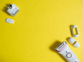 Female electric epilator in white on a yellow background. There are additional attachments nearby....