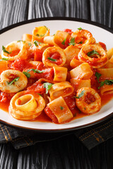 Calamarata pasta with squid sauce a traditional neapolitan recipe close-up in a plate on the table. vertical