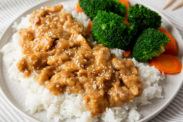 Homemade Orange Chicken with White Rice, Broccoli and Carrot on a plate, low angle view. Close-up.