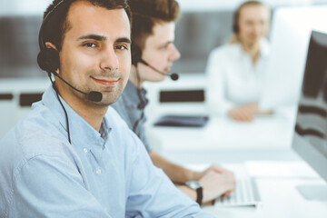 Call center. Group of casual dressed operators at work. Adult businessman in headset at customer service office. Telesales in business