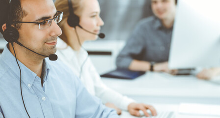 Call center. Group of casual dressed operators at work. Adult businessman in headset at customer service office. Telesales in business