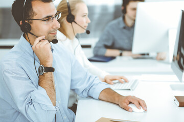 Call center. Group of casual dressed operators at work. Adult businessman in headset at customer service office. Telesales in business