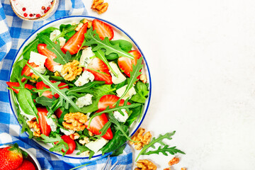 Summer Strawberry Salad. Spinach leaves, arugula, walnuts, blue cheese on gray background. Healthy food concept. Flat lay, top view