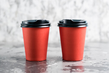 Two paper cups for tea or coffee to go red on a gray background copy space. Concept for the development of the restaurant business and food delivery during quarantine covid 19