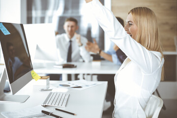 Fototapeta premium Business woman looks happy and excited at workplace in modern office. Secretary or female lawyer working for pleasure and success