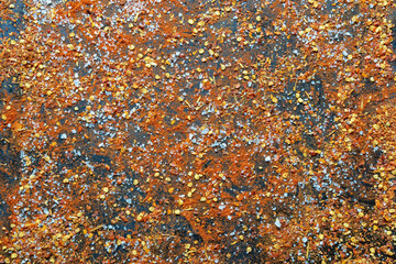 Salt and crushed hot paprika scattered on black baking sheet, background