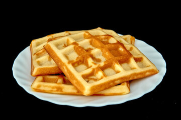 Belgian waffles on a white plate and on a black background