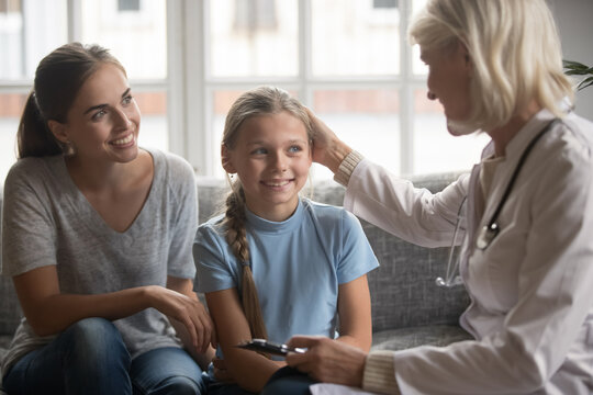 Young Caucasian Mother And Small Teen Daughter Visit Female GP Or Doctor For Health Checkup. Caring Woman Nurse Or Therapist Comfort Little Girl Child Patient At Examination In Hospital Or Clinic.