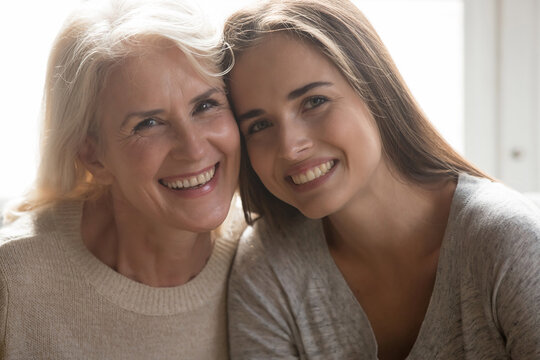 Close up headshot portrait of smiling mature mother and grownup girl child hug cuddle show love and care. Profile of happy older Caucasian mom and adult daughter pose together. Family concept.