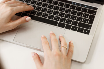 A girl student learning distance training course study work at home office. Young women's hands typing on a laptop, close-up. The girl is working on a laptop on white working desk