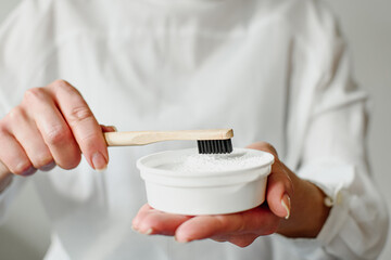 A female hand holds a bamboo toothbrush with tooth powder. Ecological products. Eco life, no waste.