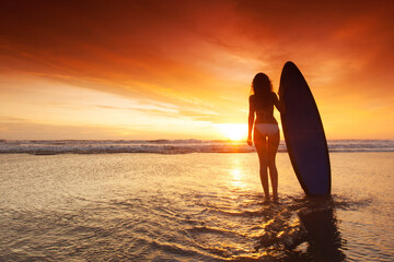 Fototapeta na wymiar Woman holding surfboard at sunset