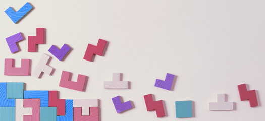 Different colorful shapes wooden puzzle blocks on pastel color background. Geometric shapes in different colors, top view