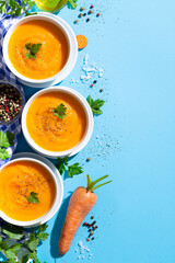 Carrot soup bowl with carrot on blue background  Top view. Vertical format with copyspace.