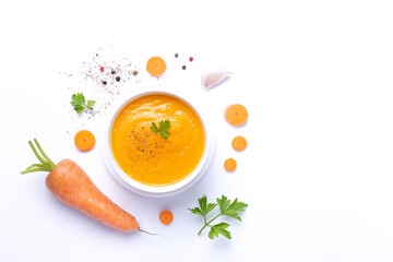 Carrot soup bowl with carrot  isolated on white background with copy space. Top view.