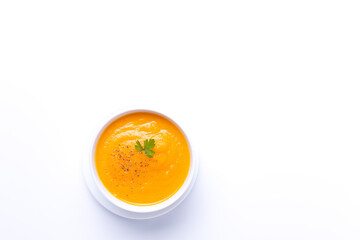 Bowl of carrot soup isolated on  white background with copyspace. Top view.
