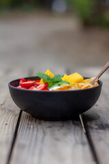 greek yogurt with mango strawberrise conflex in black bowl on wooden table top view