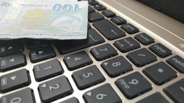 Short video with the concept of e-commerce with money dropped on the laptop's keyboard in close-up.