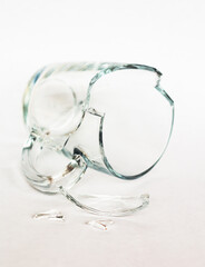 broken transparent cup on white background closeup, shards of glass mug, crash and accident concept