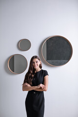 Portrait of an elegant smiling female office worker in a black dress against a background of modern mirrors