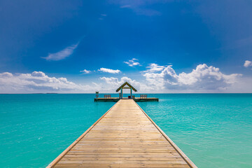 Fototapeta premium Tropical pier to paradise island beach. Amazing ocean lagoon, sea horizon under blue sky. Idyllic, meditation, inspiration scenery. Wellbeing, relaxation, positive thinking. Travel, summer wellness
