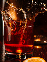 a glass of whiskey with an ice cube and orange peel decor. On a wooden bar