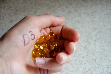 Vitamin D3 capsules in the palm with copy space. Health care concept. Close up woman hand with pills. Healthy nutrition, body support, doctor's recommendation.