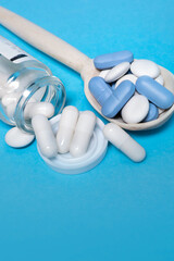 Pills tablets capsules close-up. On a blue background, a jar of medicine. White pills on background
